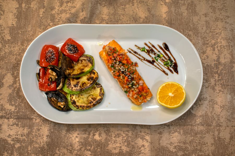 A clean, whole-food plate — glazed salmon with grilled peppers, zucchini and lemon, no processed carbs